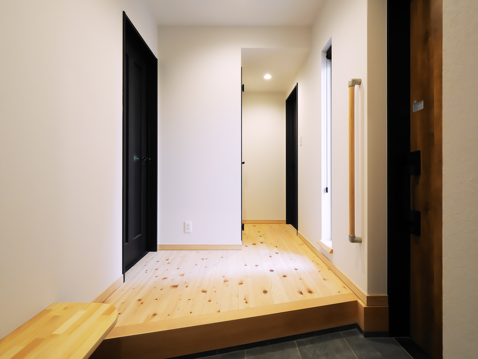 木製ドアと白壁でまとめた住宅内部の廊下空間
