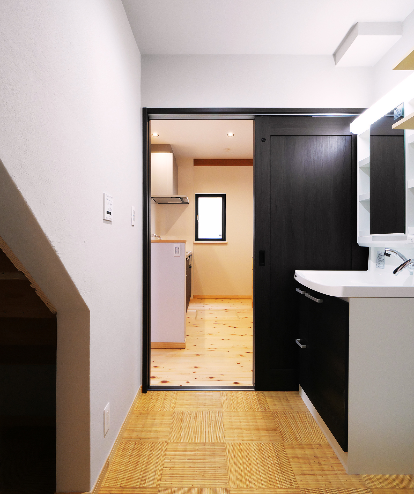 階段下に配置された洗面スペースと奥に続くキッチン