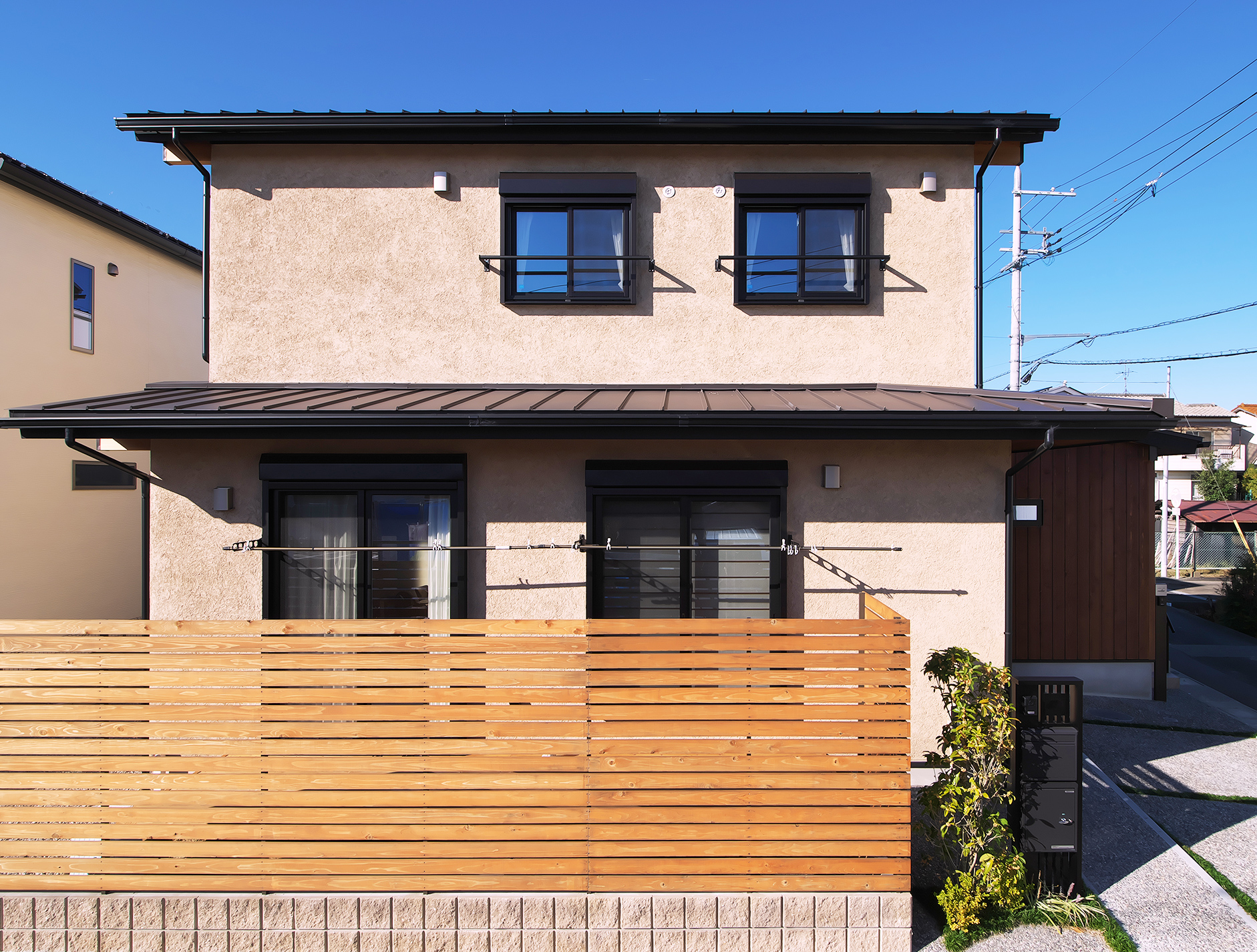 正面から見た木塀と塗り壁が印象的な二階建て住宅の外観