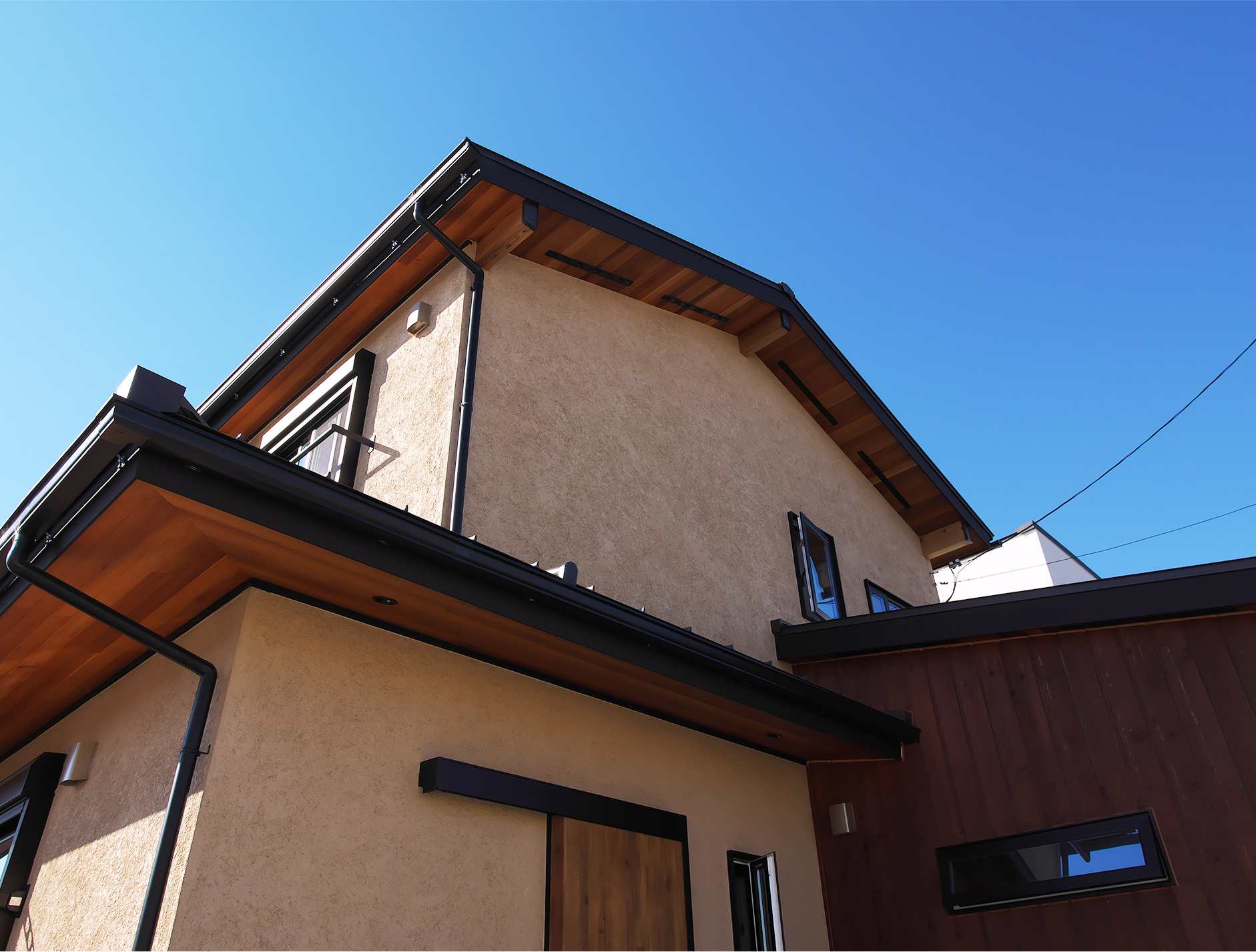 塗り壁と軒天が特徴的な住宅外観の見上げカット
